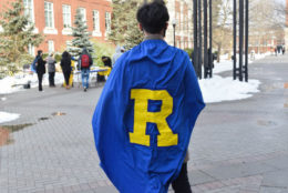 the back of a male student wearing blue cape and a yellow R