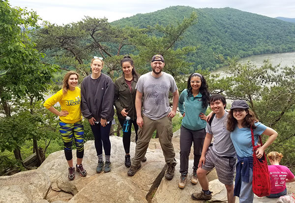 Group of people posing on durking a hike, with hill and valley in background