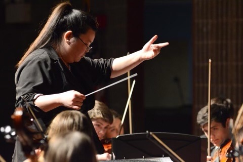 female music conductor guiding an orchestra