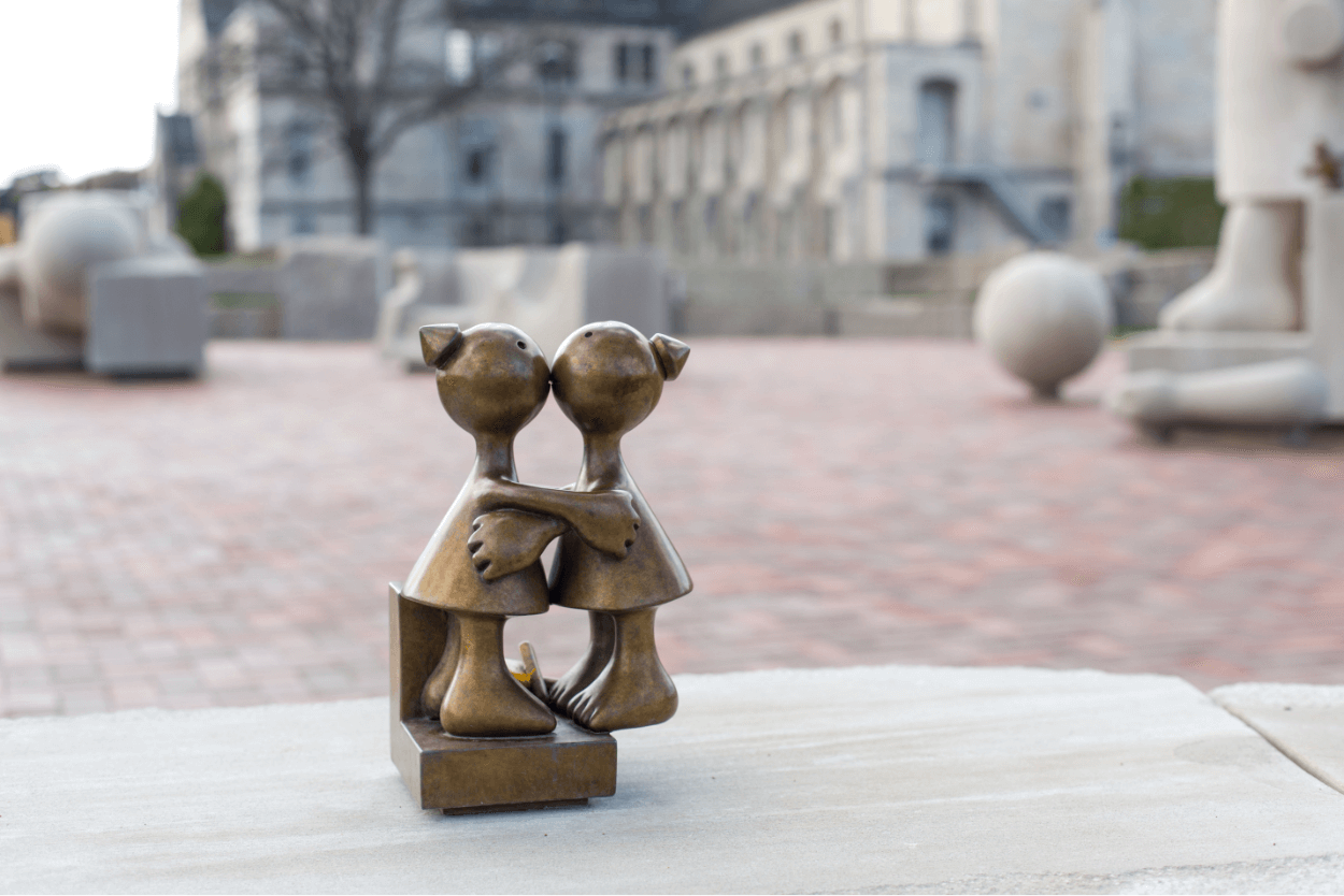 Statue of boy and girl figures kissing. Created by Tom Otterness at University of Rochester Memorial Art Gallery.