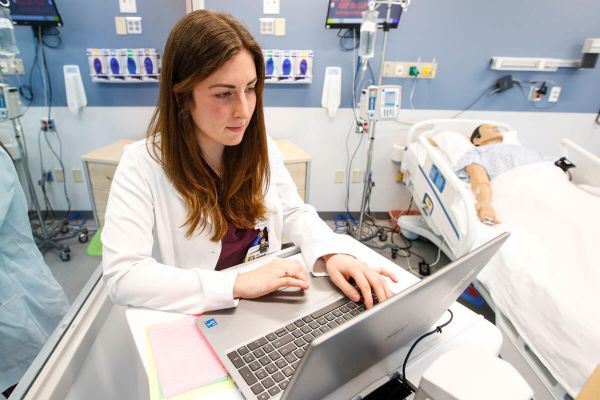 Nurse smiling in front of a computer.