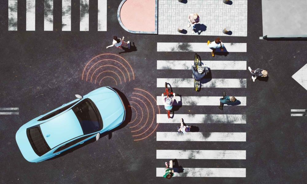 Aerial view of a crosswalk with pedestrians and cyclists, and a blue car with sensor indicators.