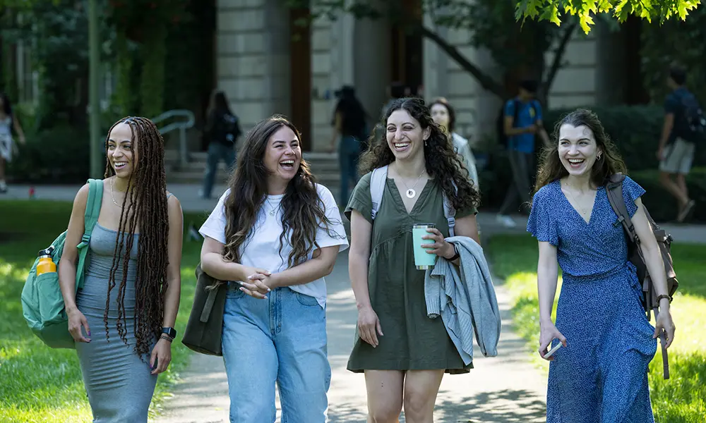 Four students walk to class on a fall day.