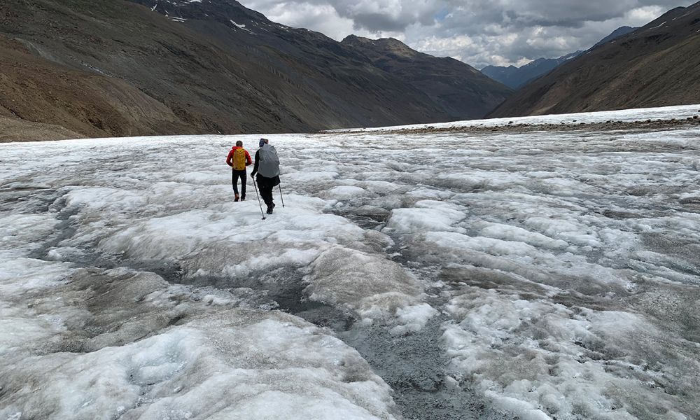 Two hikers walk off into the distance along a glacier.