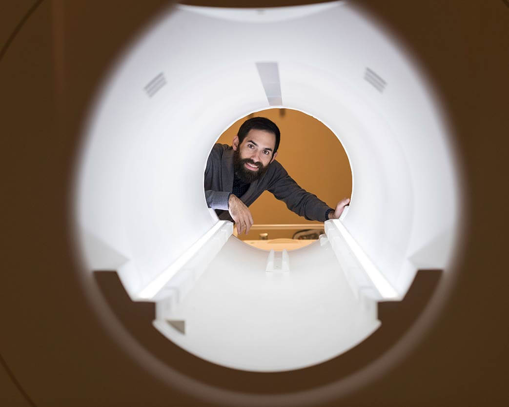 Researcher smiles while looking through an MRI machine