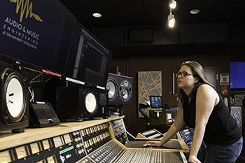 A person working the board in the control room of s sound studio.