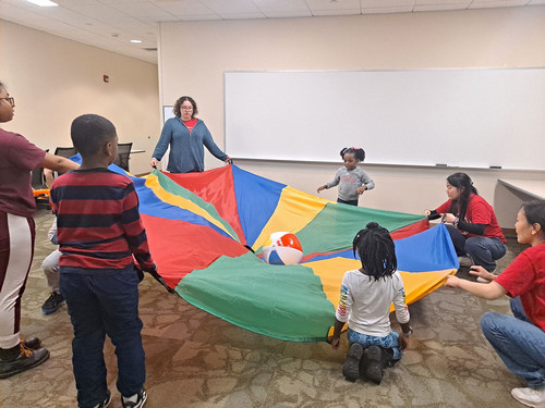 LEAP leaders playing with a parachute with children.