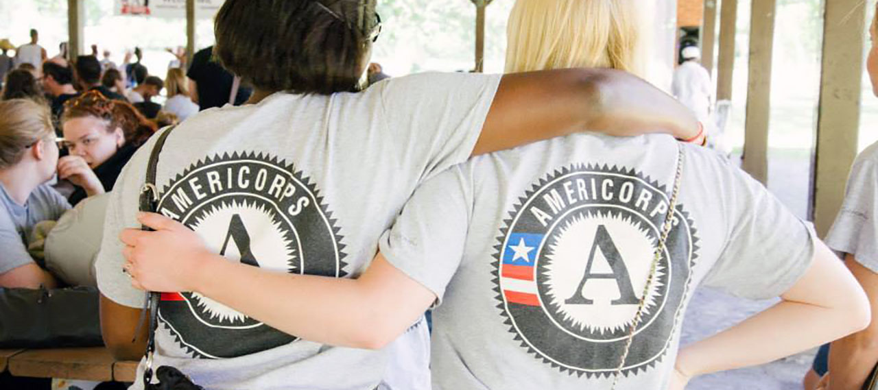 Two Americorp volunteers with their arms around each other's shoulders.