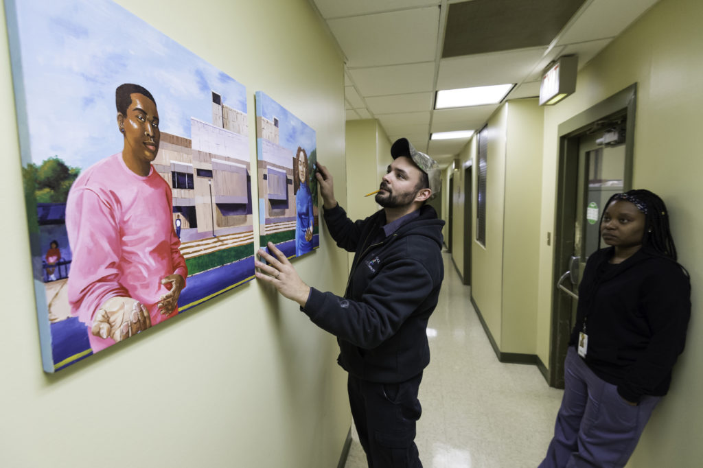 Students hanging artwork at the Jordan Health Center.