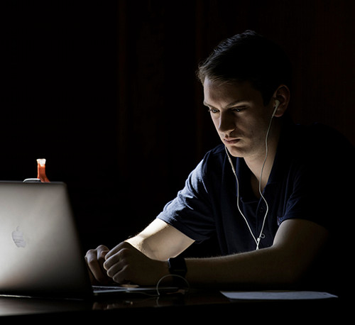 A student peering at their laptop in contemplation.