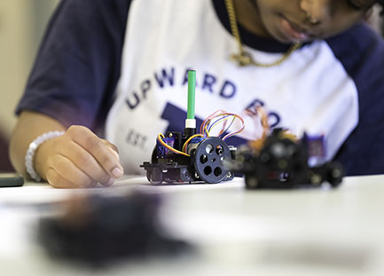 An Upward Bound student working on a robot.