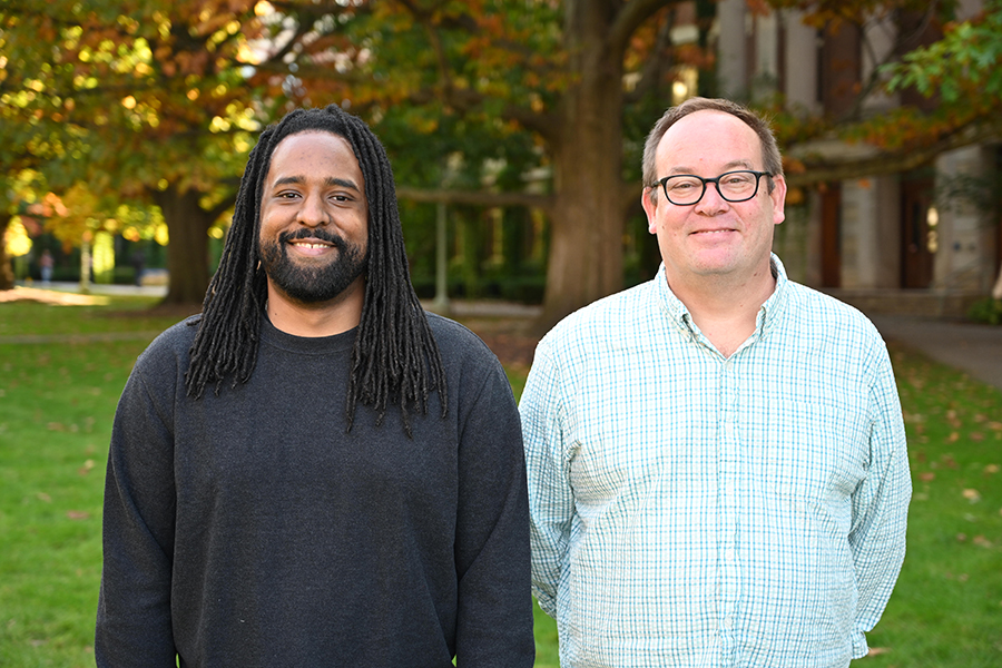 Two people smiling at the camera in an outdoor setting.