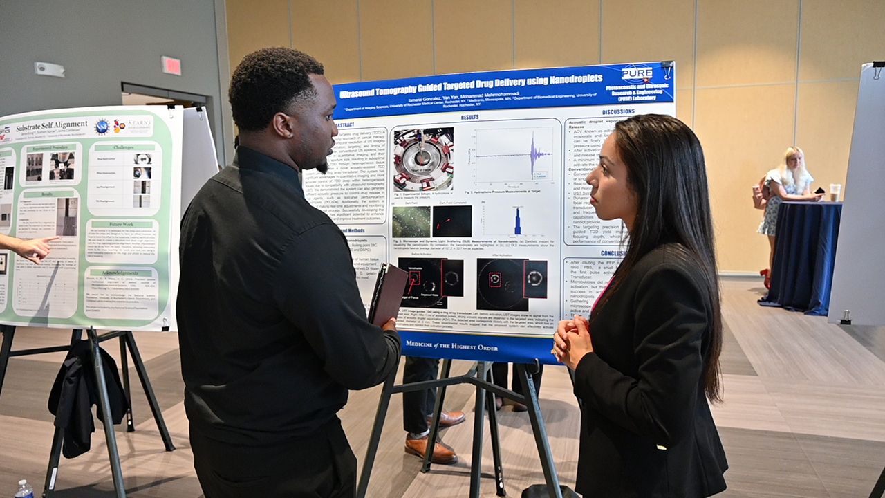 A student presenting their research at a poster session.