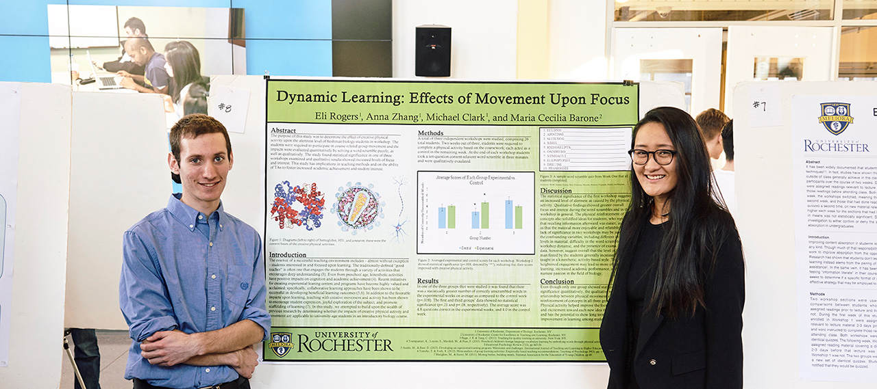 Two students standing in front of their research project poster at a poster session.