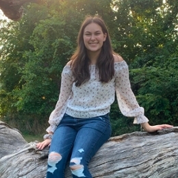 Julianna Saxena sitting on a log.