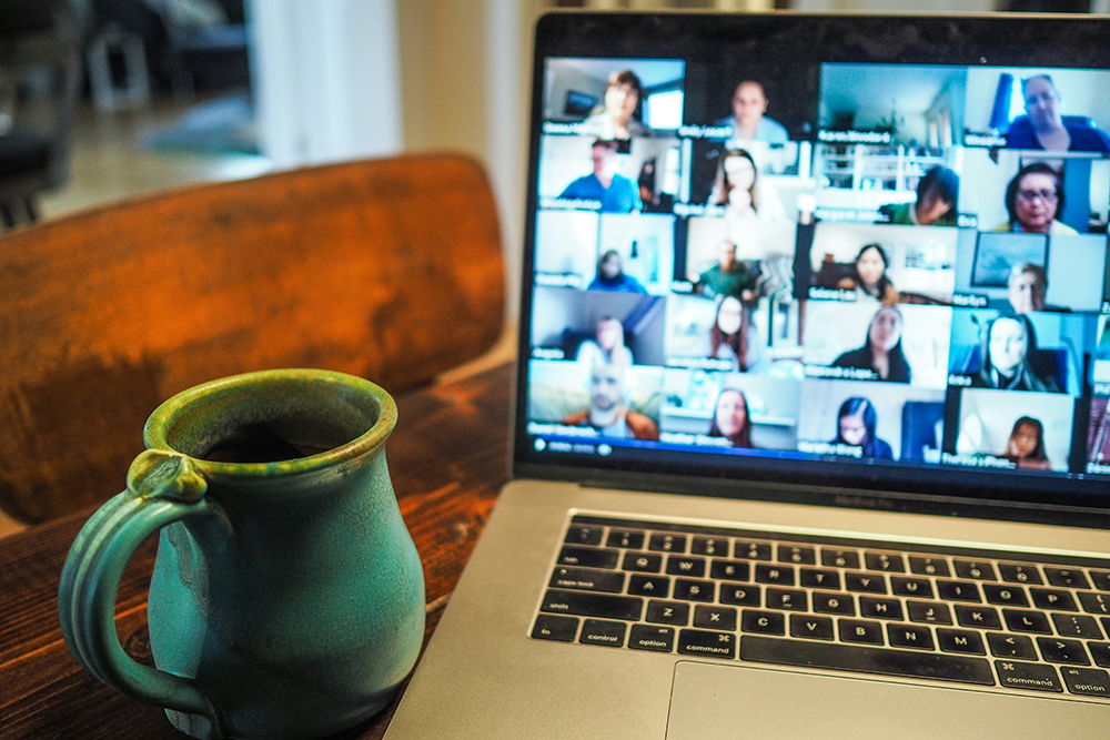 A laptop screen with an online meeting displayed with a mug in the foreground