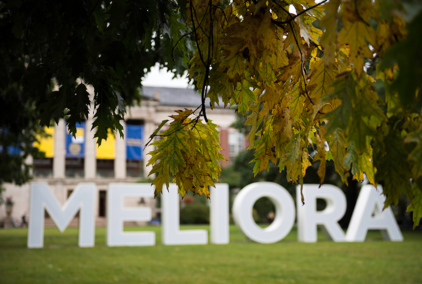 Photo of large letters spelling out Meliora Weekend on campus with autumn leaves in the foreground