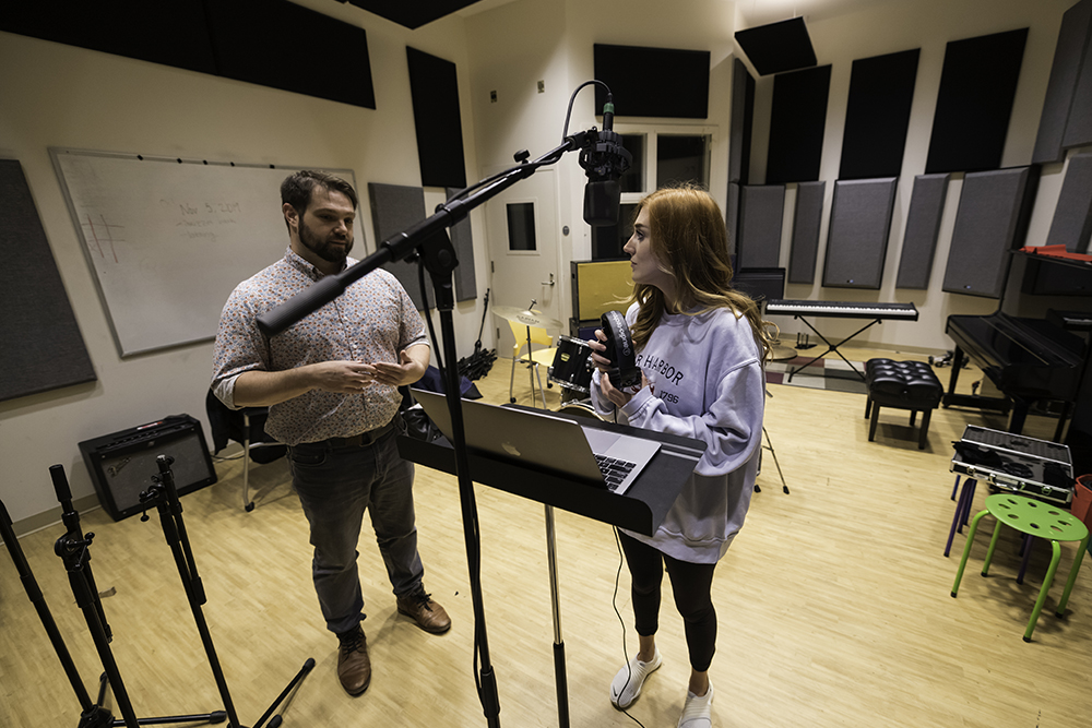 A professor and a student recording a podcast in the studio.