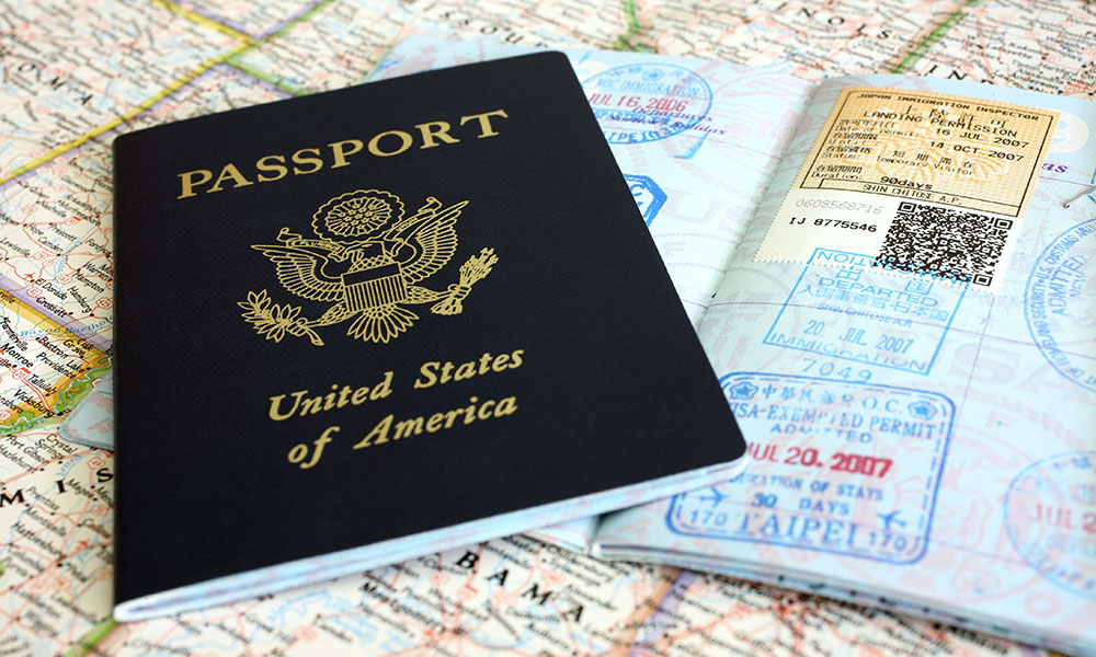 One closed and one open passport lying on a map of the US.