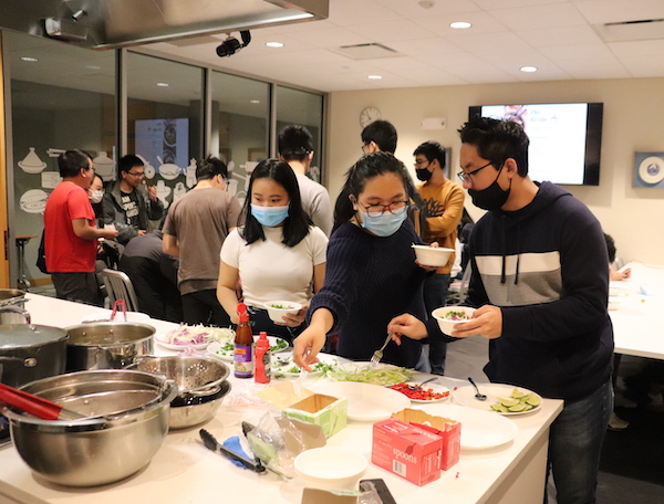 Students in a crowded kitchen eating