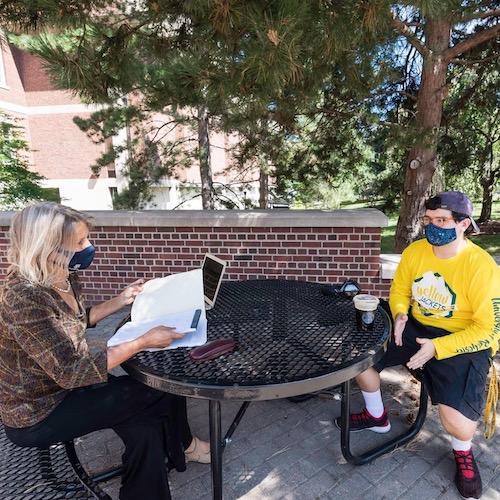 Two students outside sitting at a table