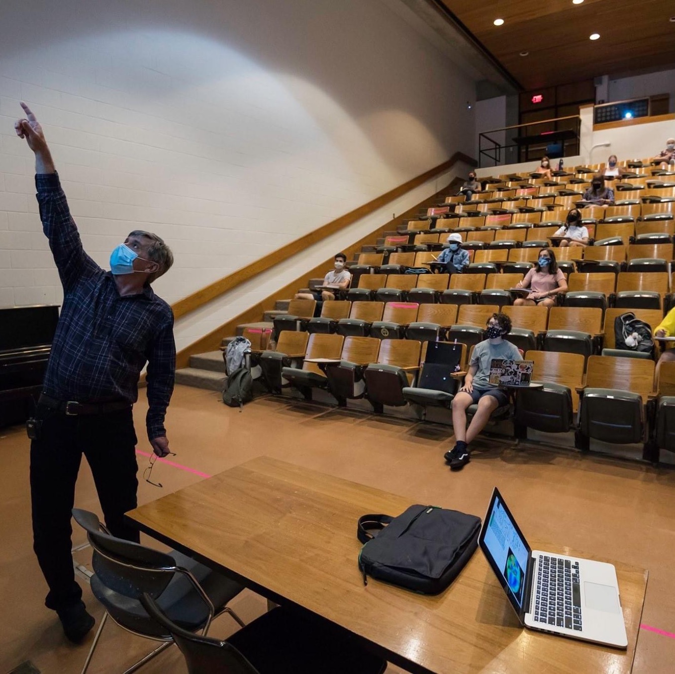 Professor pointing to screen in front of lecture hall