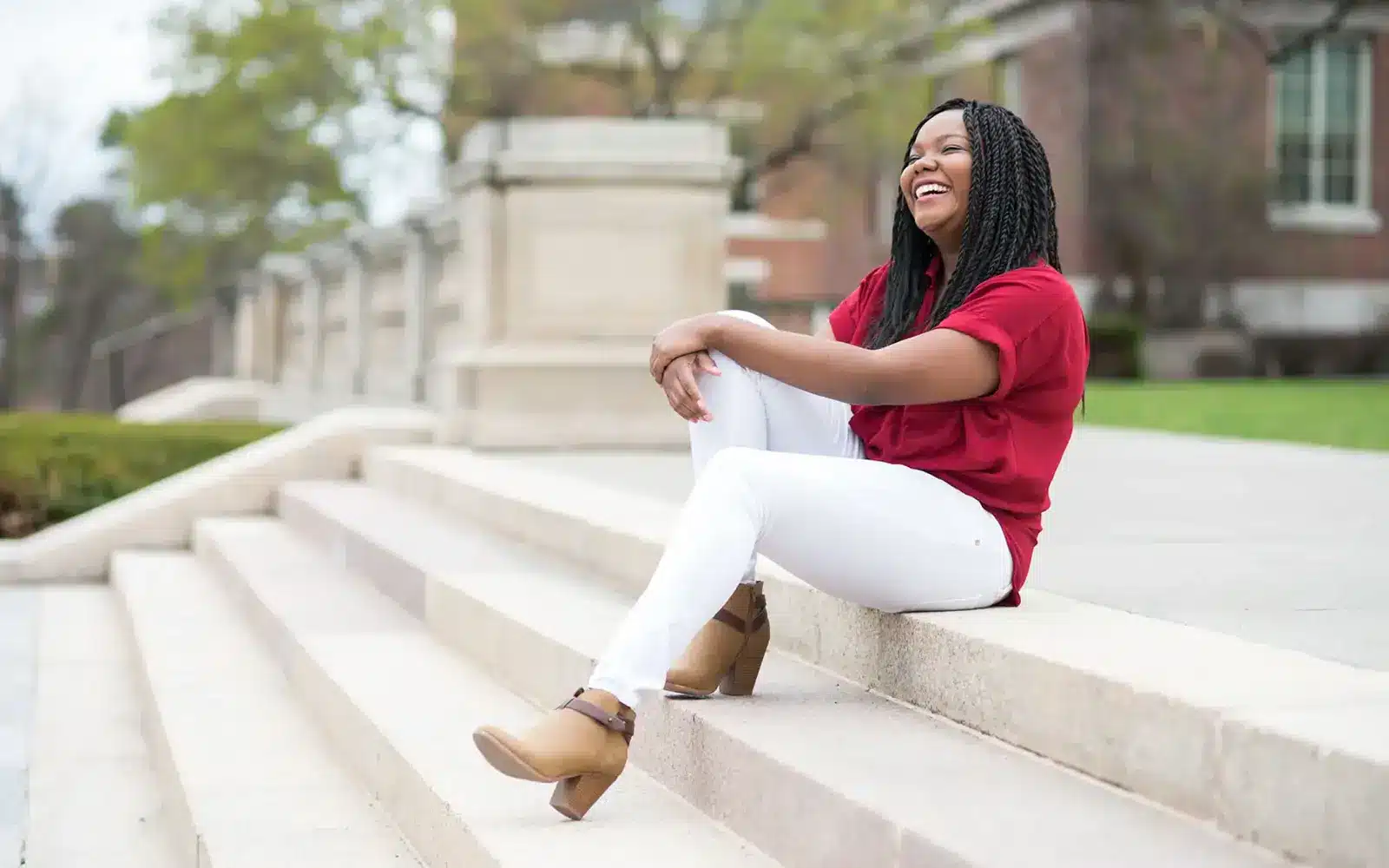 Woman sits on steps in front of a university building.