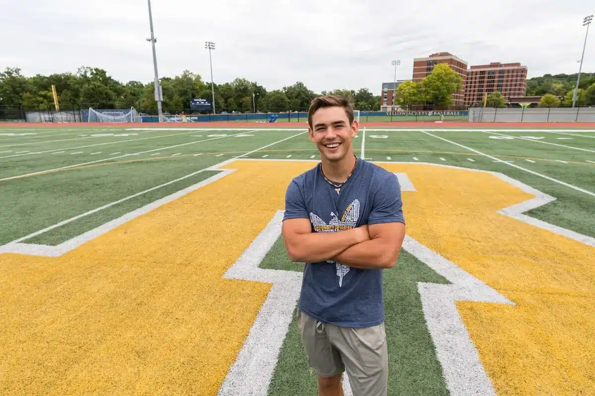 James Bentayou stands on the football field and poses for a picture.