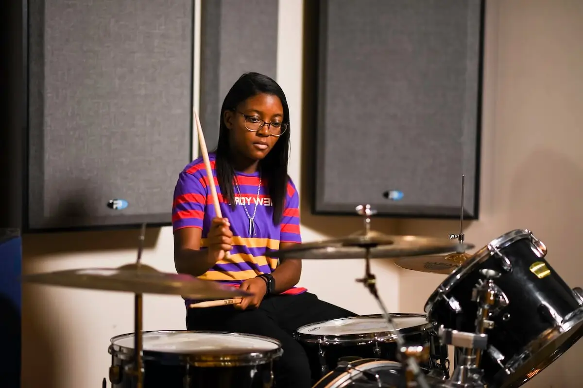 Sanaa Finley plays the drums sitting at a drum kit.