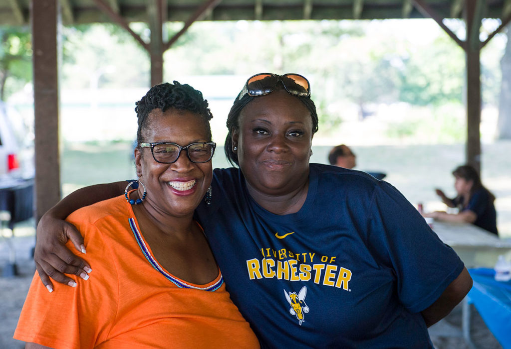 two women, one in University of Rochester t-shirt, smiling and hugging
