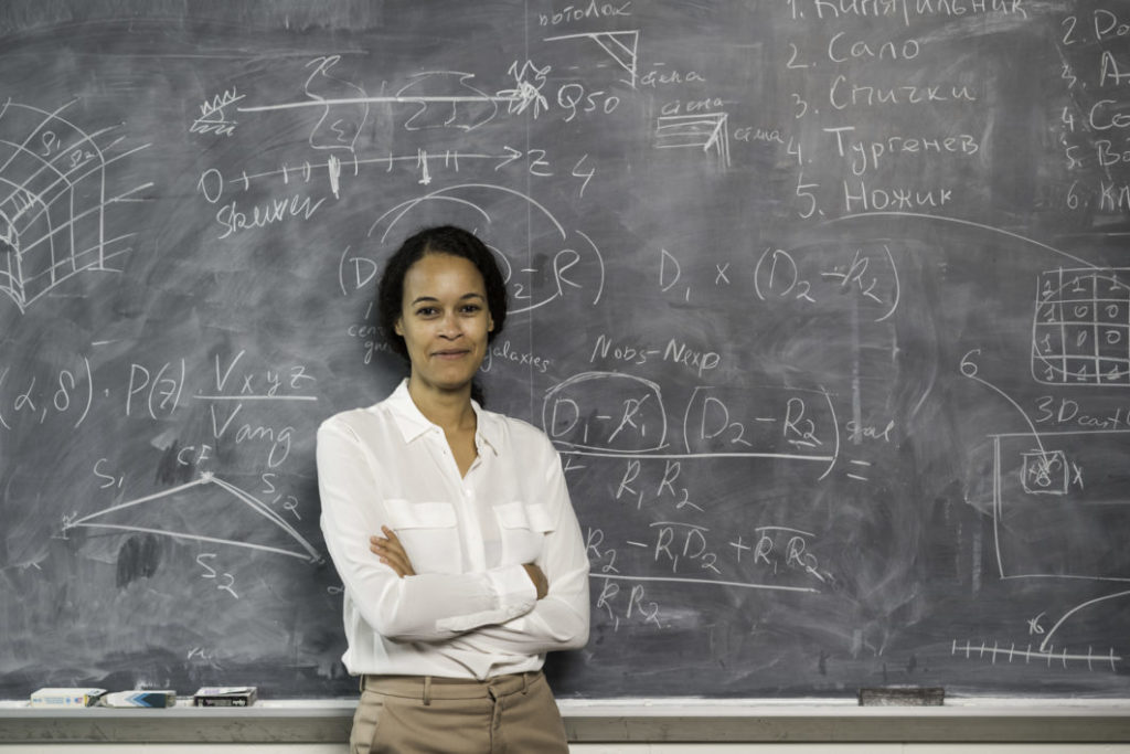 University of Rochester professor in front of her work on a chalkboard