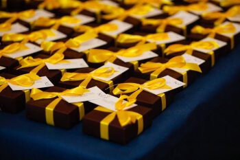 A table laid with boxed yellow ribboned gifts for the attendees at the George Eastman Circle Faculty & Staff Reception held on March 30, 2023 within Rochester New York. .