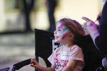 A girl with colorful face paint smiling