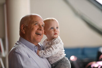 An older man holds an infant at the George Eastman Circle Family Celebration, held on April 27, 2023 within Rochester New York.