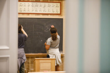 2 people writing on a chalkboard
