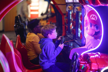 A kid playing a Mario arcade game