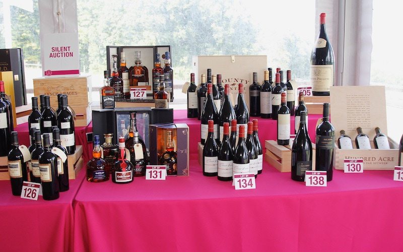 several auction lots of wine on a table with pink covering