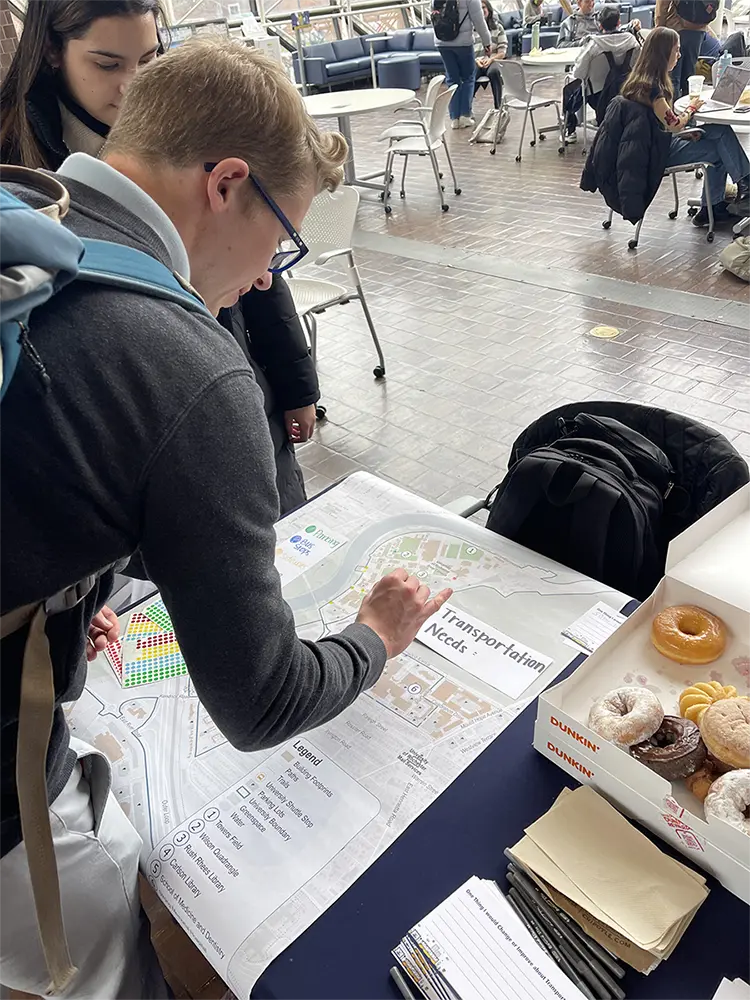 A student places colored markers on a map displayed in Wilson Commons to indicate his transportation needs.
