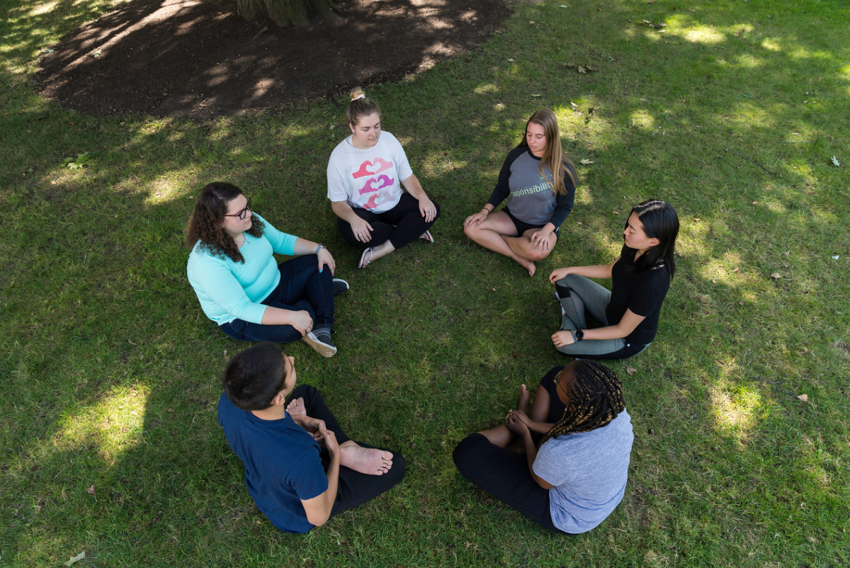 Students sitting in circle formation on the lawn