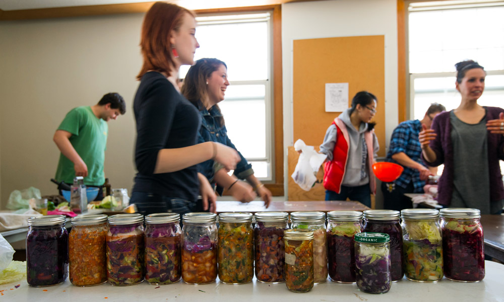 students standing behind a table full of jars of kimchi