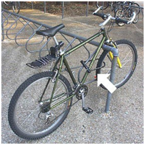 picture of a bike locked to a bike rack, with an arrow pointing to the bike frame where the lock should be placed.