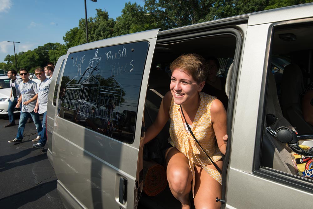 students gets out of a car, windows are decorated with drawings of Rush Rhees Library