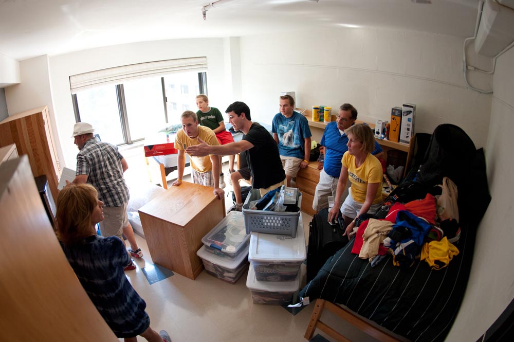 students and families re-arrange furniture in a dorm rool