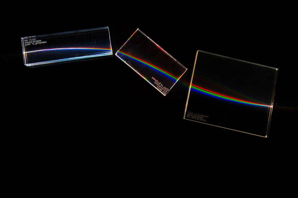 white light passing through three blocks of clear plastic and breaking into red, green, and blue light