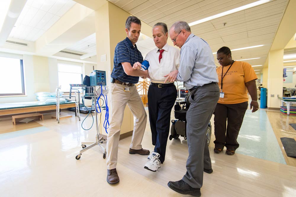 physical therapists assist Bradford Berk as he walks during a therapy session