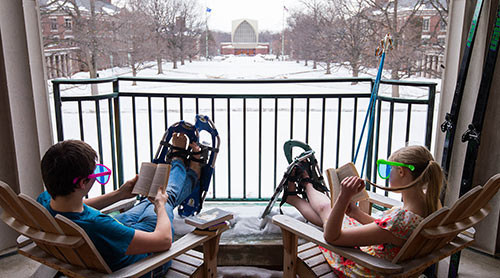 two students wearing snow shows read on the Rush Rhees Library balcony