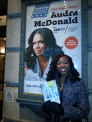 student posing with Audra McDonald poster outside theater