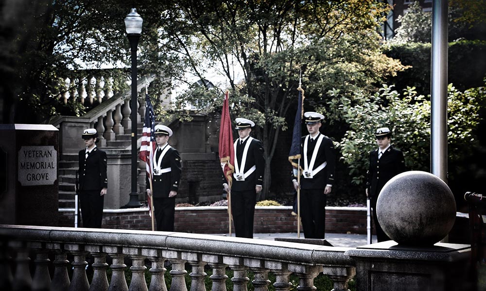 Five uniformed NROTC students standing at attention in Veterans Memorial Grove.