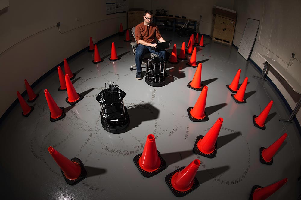 professor directs small robot through maze of traffic cones