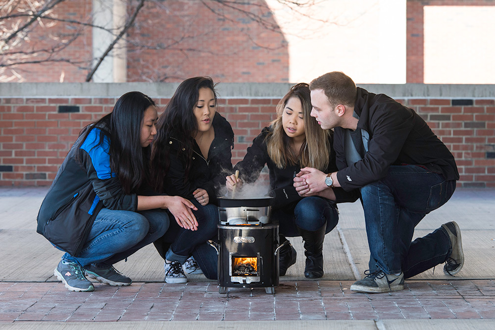 students sitting around a cooking stove